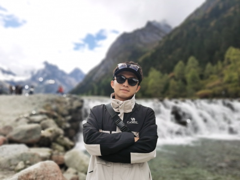 Yunjie, creator of FirstTripChina, standing by a waterfall in western Sichuan